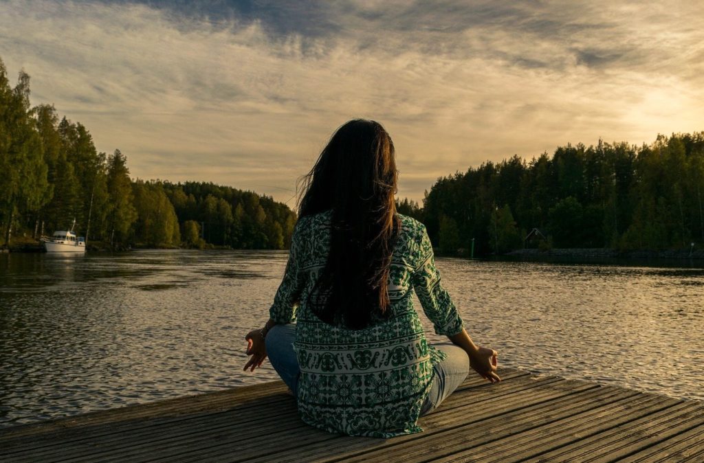 a girl sitting and doing meditation in front of rlake